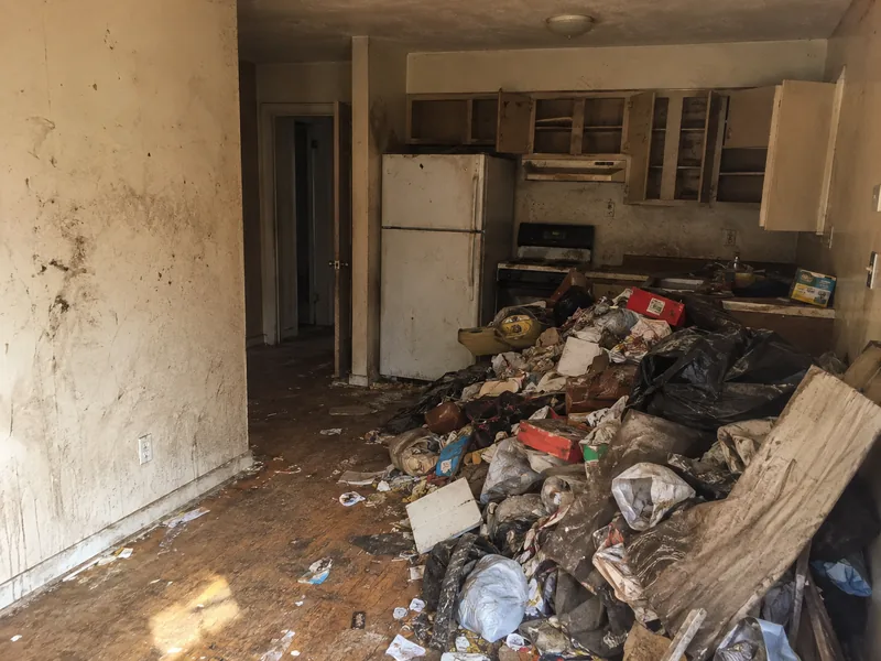 Apartment unit before work, filled with debris and damaged surfaces