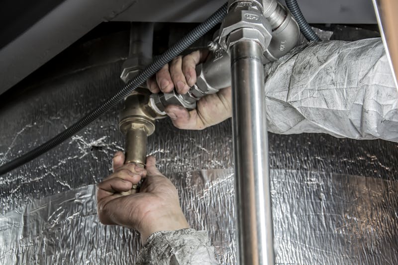 Plumber working on pipes and insulation